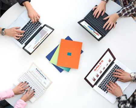 Top View of White Rounded Desk with Four Laptops and People Hands Typing on Stock Photos