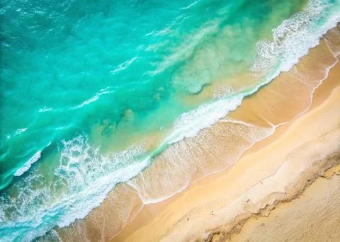 Top view of the white sand beach and the rolling foamy wave of the ocean. Stock Photos