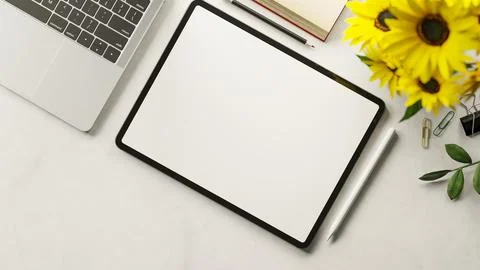 Top view white screen tablet and stylus with laptop and book aside sunflowe.. Illustrazione stock