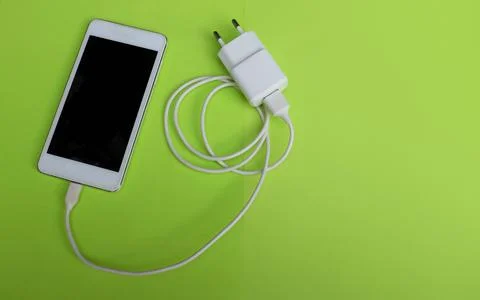 Top view  white Smartphone Plug In with Charger Adapter on green Background Stock Photos