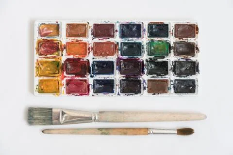 Top view: on the white surface are watercolor paints and various brushes for  Stock Photos
