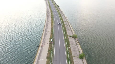 Top view of white SUV driving at dam route. Flying over auto moving at bridge Video stock 253777075