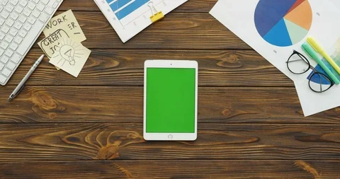 Top view on the white tablet device with a green screen lying vertically on the Stock-Footage 88423756