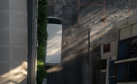 Top view of a white van parked next to a wall near a parking lot and mornin.. Stock Photos