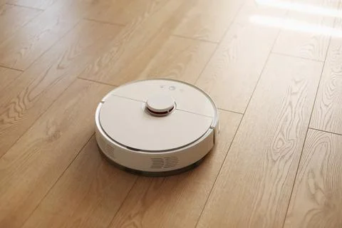Top view of white wireless autonomous robot vacuum cleaner on wooden floor... Stock Photos