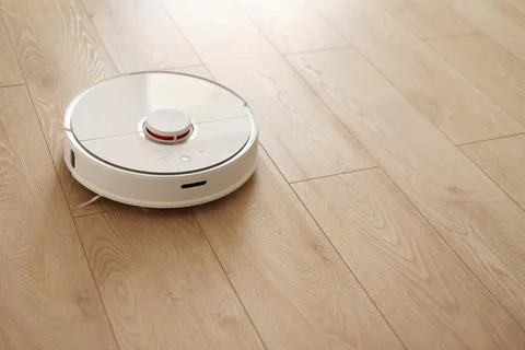 Top view of white wireless autonomous robotic vacuum cleaner on wooden floor Stock Photos