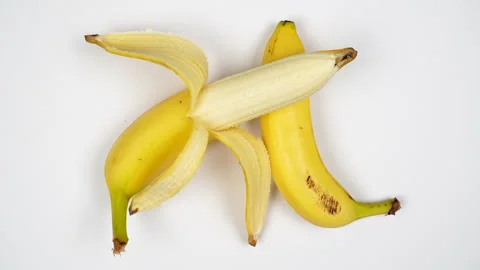 Top View Whole And Half Peeled Yellow Banana Rotating On White Background 4K Stock Footage 322143689