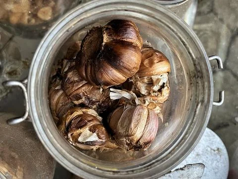 Top view of whole fermented black garlic bulbs in a glass jar. Stock Photos