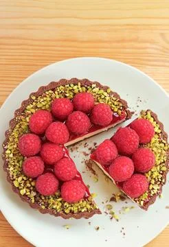 Top view of a whole raspberry tart with one slice gently pulled apart Stock Photos