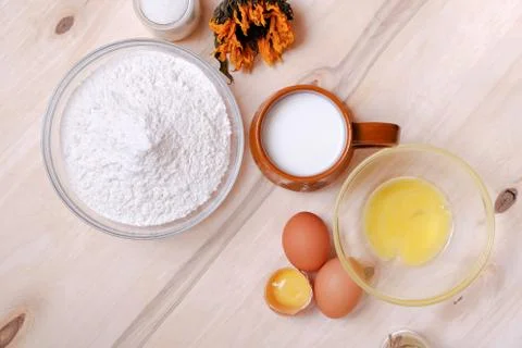 Top view: wicker basket of eggs, heap of flour, glass of milk, sugar, butter  Foto stock