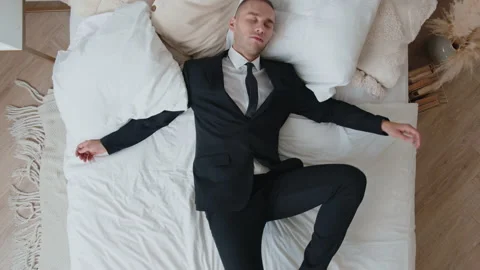 Top view of wide tired caucasian young businessman falling on bed in home Stock Footage 166300878
