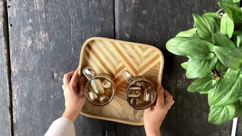 Top View of Woman Hand Serving Two Glasses of Ice Tea on Patterned Wooden Tray Stockbeeldmateriaal 337721030