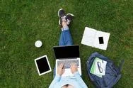 Top View Of Woman With Laptop Sitting On The Green Grass Stock Photos