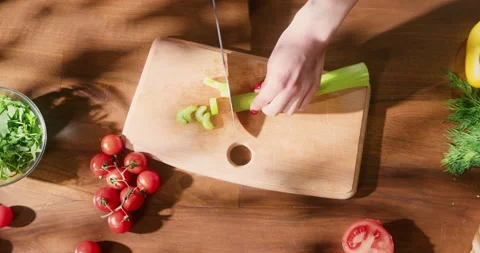 Top view of woman's hand cutting green celery stalk on chopping board. Female Video stock 150702490