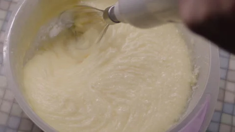 Top view, woman's hand with mixer whipping up custard for cake on kitchen table Stock Footage 304694804
