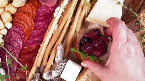 Top view of a woman's hand placing a bowl of olives on a round appetizer plate o Stock Footage 304457790