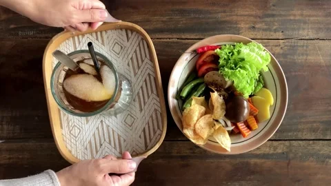 Top View of Woman's Hand Serving Glass of Ice Tea Besides Traditional Selat Solo 動画素材 337782907