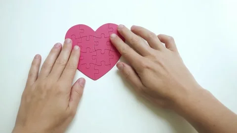 Top view on woman's hands are taken red heart shaped jigsaw from paper blocks Stock Footage 153438943