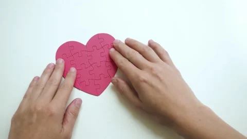 Top view of woman's hands are putten red heart shaped jigsaw from paper blocks Stock Footage 153438973