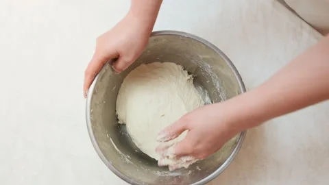 Top view of woman's hands kneading a dough in a stainless steel bowl Stock Footage 300095506