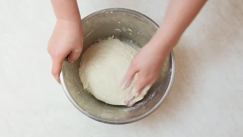 Top view of woman's hands kneading a dough in a stainless steel bowl Stock Footage 300095717