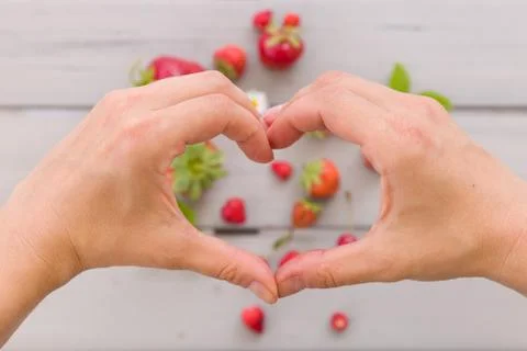 Top view on woman's hands making heart on fresh organic strawberries Foto stock