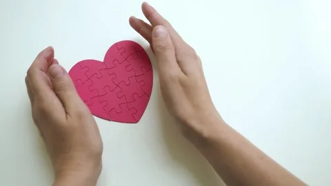 Top view of woman's hands open hided small red heart shaped jigsaw from paper Stock Footage 153439003