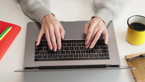 Top view of womans hands typing on laptop keyboard at a white desk Stock Footage 323213316