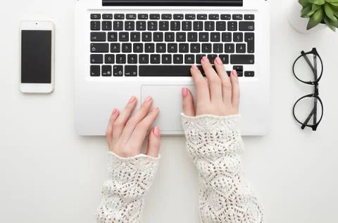 Top view of woman's hands typing on laptop keypad placed on white office desktop Stock Photos
