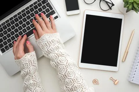 Top view of woman's hands typing on laptop keypad placed on white office desktop Stock Photos