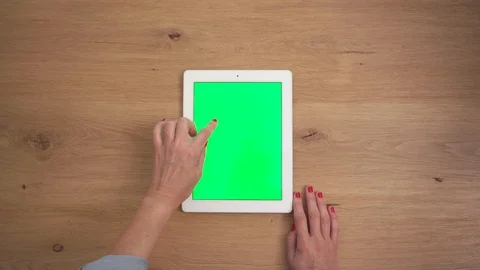 Top view of a woman's hands using a chroma green screen tablet on a wooden de Stock Footage 128598248