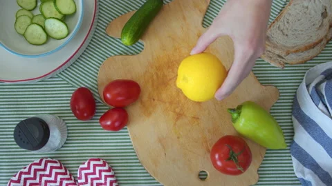 Top view women's hands cuts lemon with knife on cutting board with a variety of Video stock 137827772