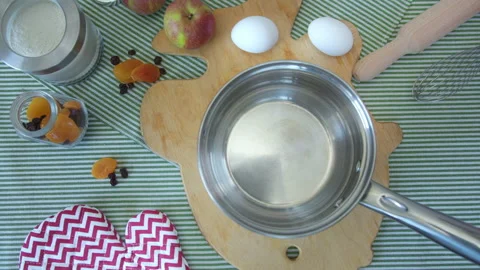 Top view women's hands pour milk into metal pan on table in kitchen, preparing Stock Footage 137829205