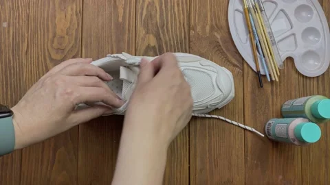Top view of women's hands pulling out shoelace from sports sneaker. Stock Footage 163624529