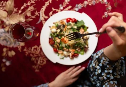Top view of women's hands at the table in a cafe eating salad with shrimp Stock Photos