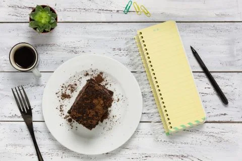 Top view of a wooden table with empty notebook, coffee, cake and cactus Stock Photos