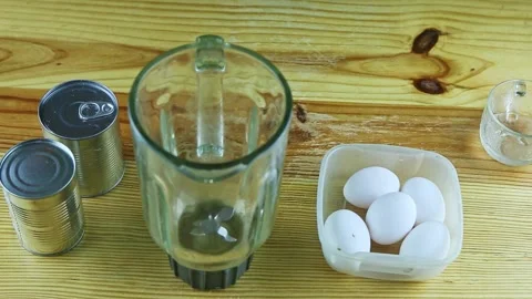 Top view on wooden table served with empty blander, white eggs, and steel cans Stock Footage 140517655