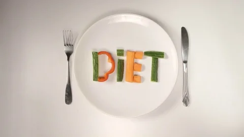 TOP VIEW: Word DIET from a vegetables on a white dish (stop motion) Stock Footage 75020904