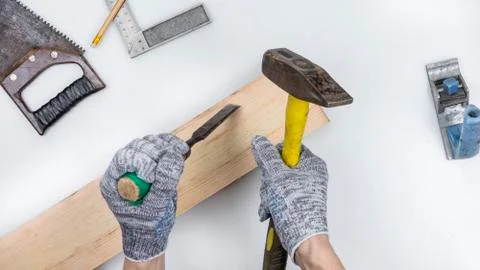 Top view of a work table in a carpentry workshop. Hands in gloves hold a chisel Stock Photos