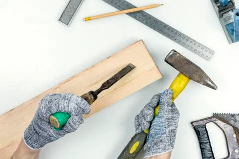 Top view of a work table in a carpentry workshop. Hands in gloves hold a chisel Stock Photos