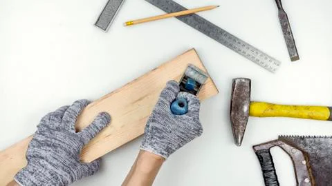 Top view of a work table in a carpentry workshop. Hands in gloves hold a wooden Stock Photos