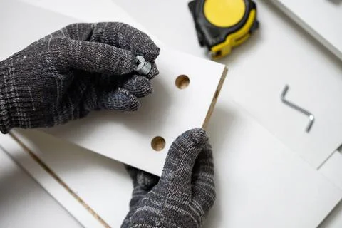 Top view of worker hands in protective gloves inserting metal cam lock fastener Stock Photos