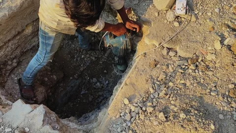 Top view of worker using drilling machine in dug section of road, broken Stock Footage 334363775