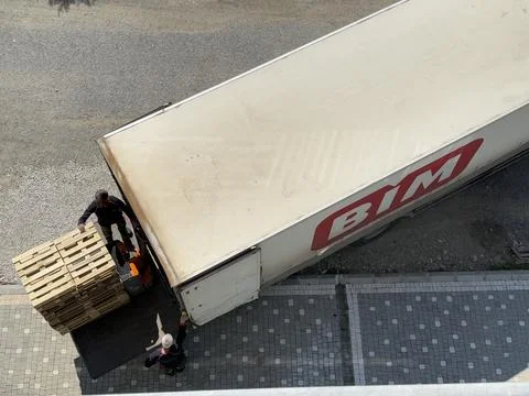 Top view of workers loading wooden pallets onto truck with manual forklift Stock Photos