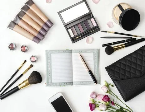 Top view of the working area notebook with pen and decorative cosmetics for Stock Photos