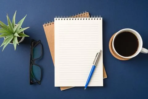 Top view of a workspace with a blank notebook, pen, glasses, coffee, and plan Stock Photos