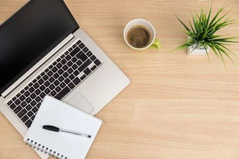 Top view of workspace. Table desk with laptop, coffee, notepad, pen and plant Stock Photos