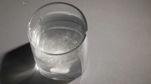 Top view of yellow effervescent tablet of vitamin C dissolves in glass of water Stock Footage 105018634
