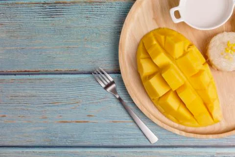 Top view Yellow half  mango with small fork. Mango fruit cubes on the Blue wo Stock Photos