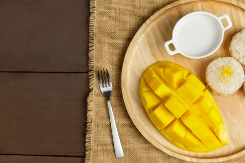 Top view Yellow half  mango with small fork. Mango fruit cubes on the wooden  Stock-Fotos